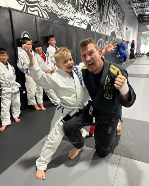 Black Belt Coach making fun faces with Kid during Kids Jiu Jitsu