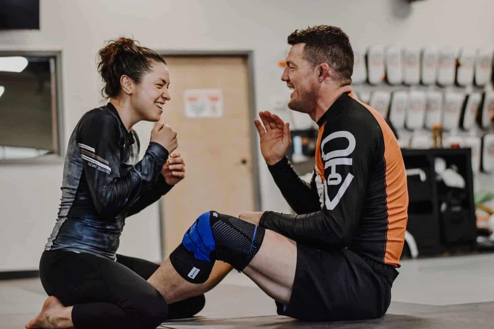 Woman and Man smiling and having fun about to get a roll in jiu jitsu at SBG